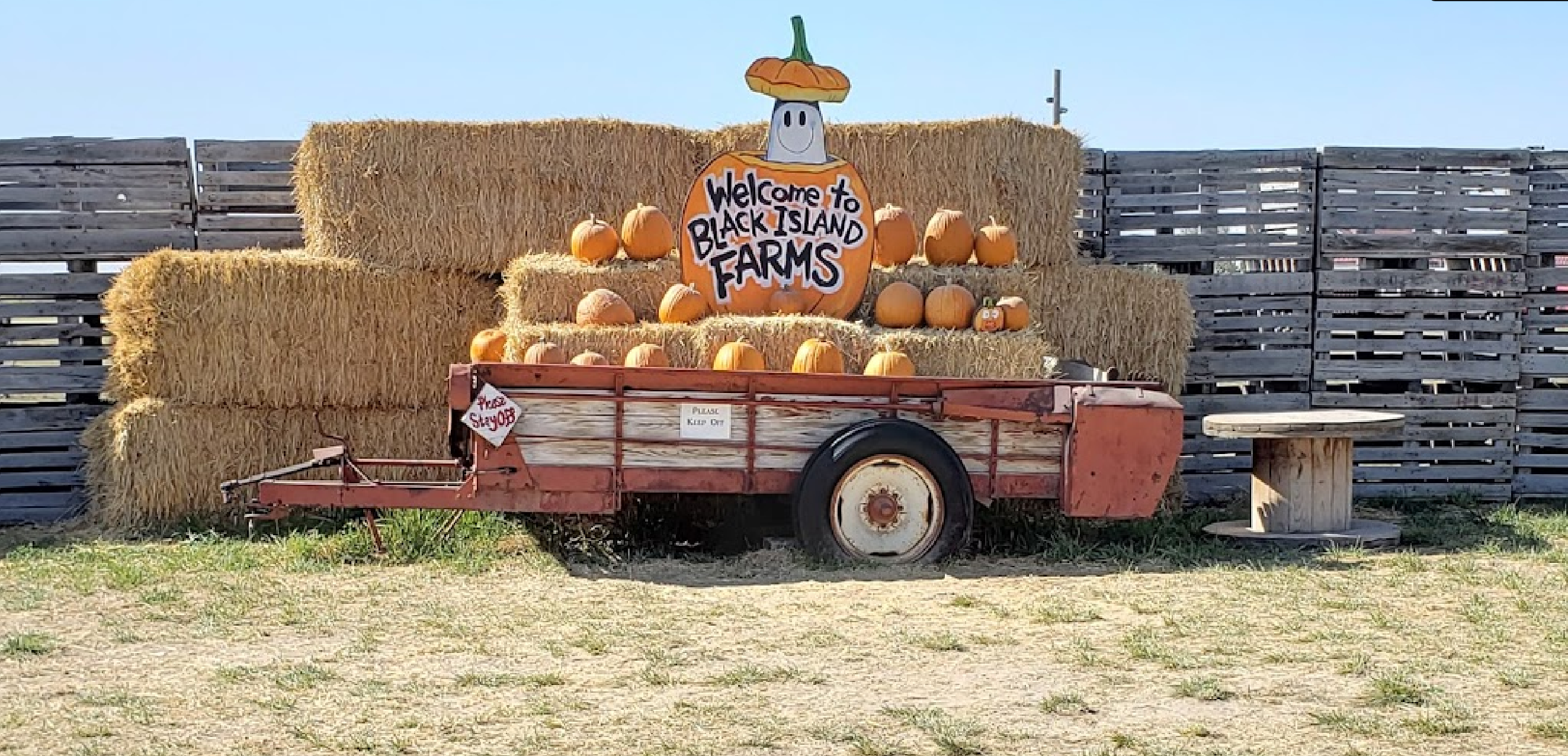 Trailer with hay bales and pumpkins on deck, and a welcome sign